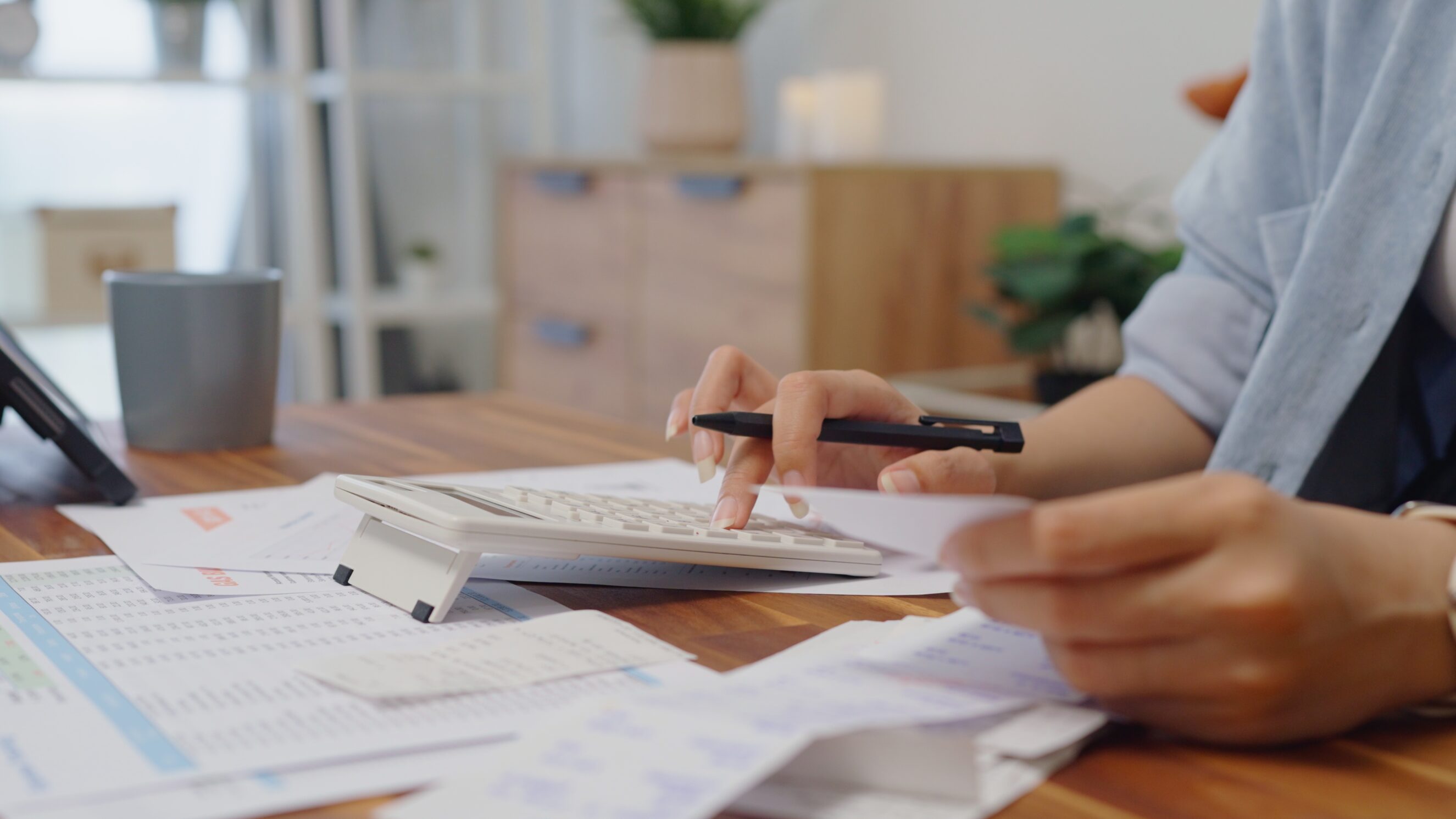 close up woman hands calculates on calculator for personal finance, paysckeck paper receipt expense biil statement,planning budgets of monthly personal balance at home.